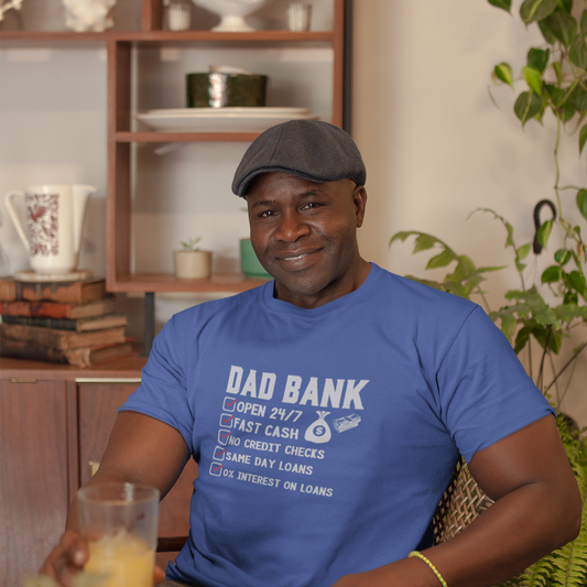 Man shown is wearing our "Dad Bank" T-Shirt. This clever design features a checklist of services provided by the "Dad Bank" with all items checked: Open 24/7, Fast Cash, No Credit Checks, Same Day Loans, and 0% Interest on a True Royal t-shirt.